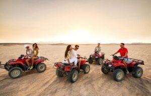 A family enjoying a thrilling Super Safari adventure, riding quad bikes across the golden desert dunes of Marsa Alam.