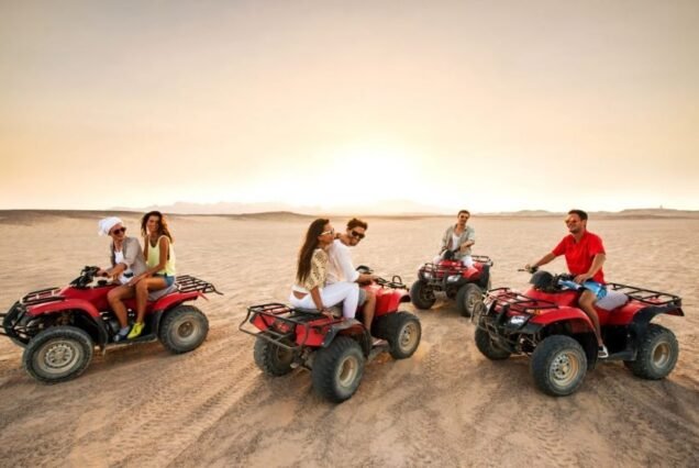 A family enjoying a thrilling Super Safari adventure, riding quad bikes across the golden desert dunes of Marsa Alam.